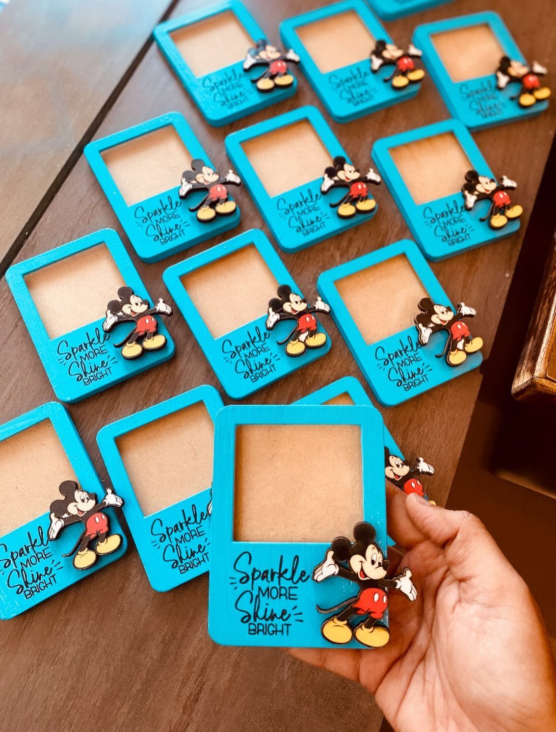 Blue polaroid-style frames with Mickey Mouse figures and inspirational text on wooden table