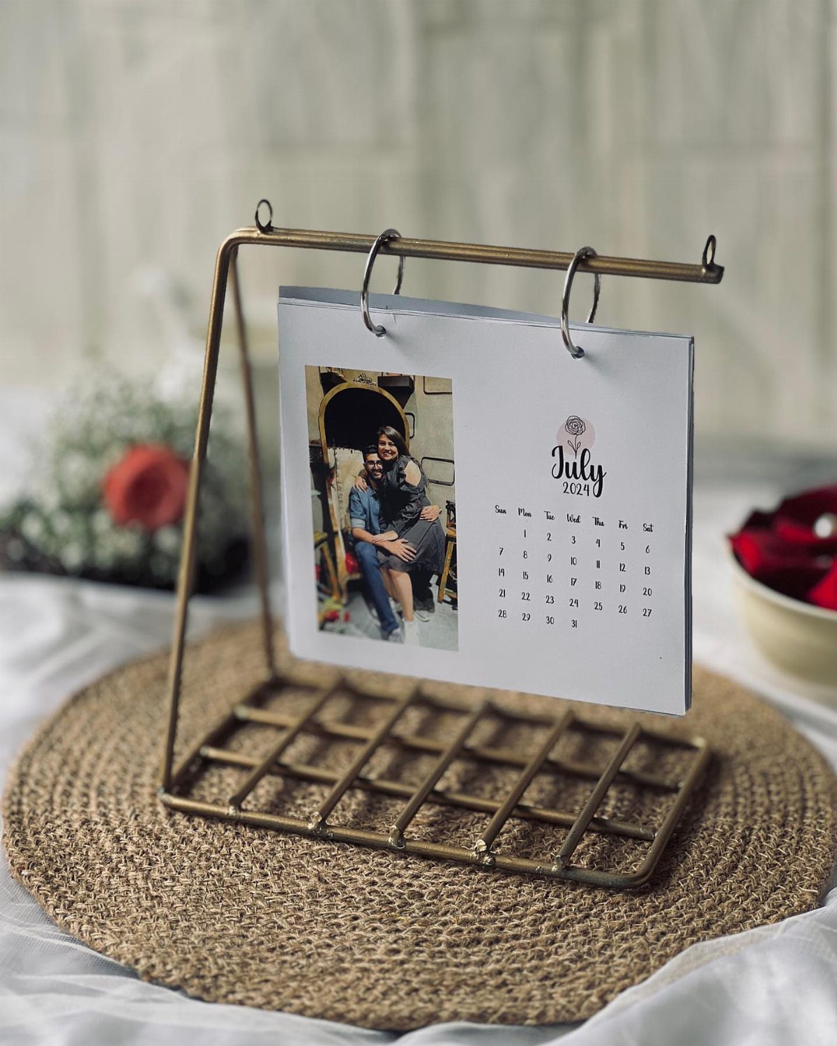 Desk calendar with a couple's photo on a gold metal stand over jute mat
