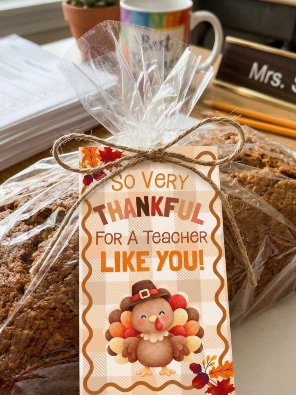 Baked bread loaf wrapped in plastic with a thankful teacher gift tag.