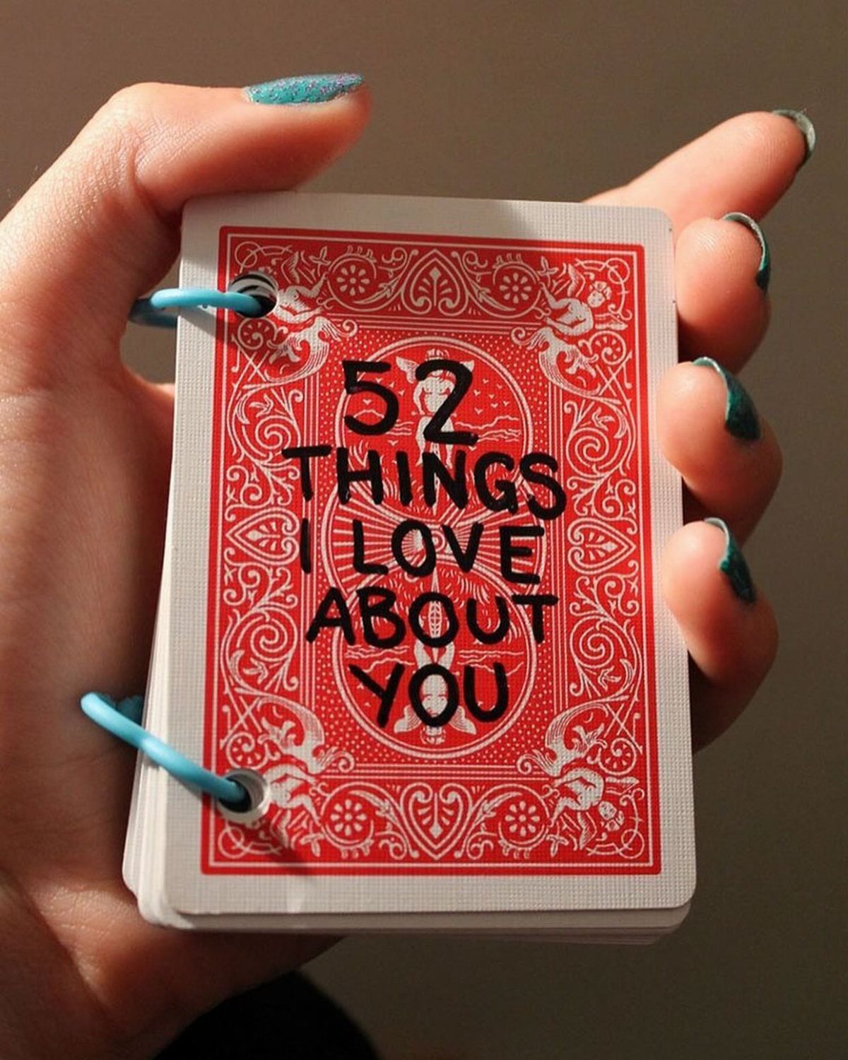 Hand holding a deck of playing cards titled 52 Things I Love About You