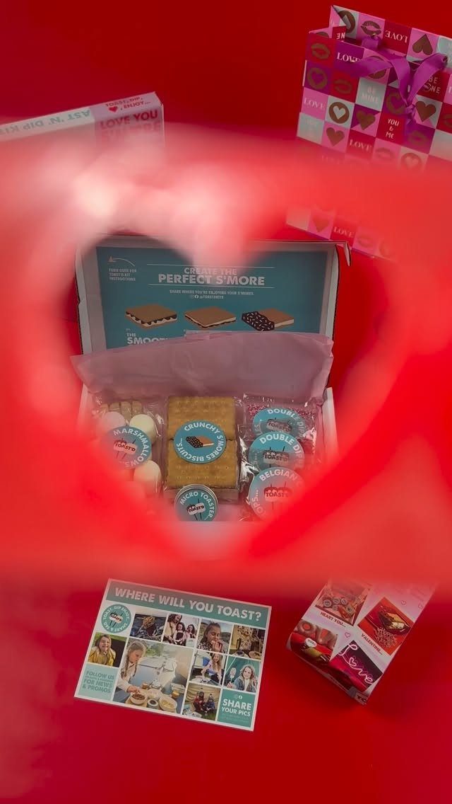 S'mores kit with crackers and chocolate viewed through a red heart-shaped frame.