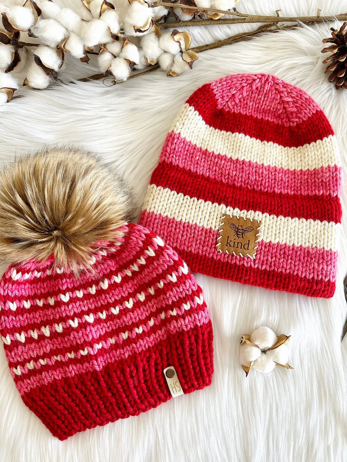 Two red, pink, and white striped knit beanies on white faux fur.