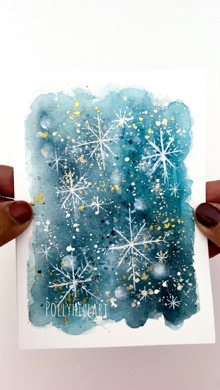 Watercolor card with white snowflakes and gold speckles on a blue background.