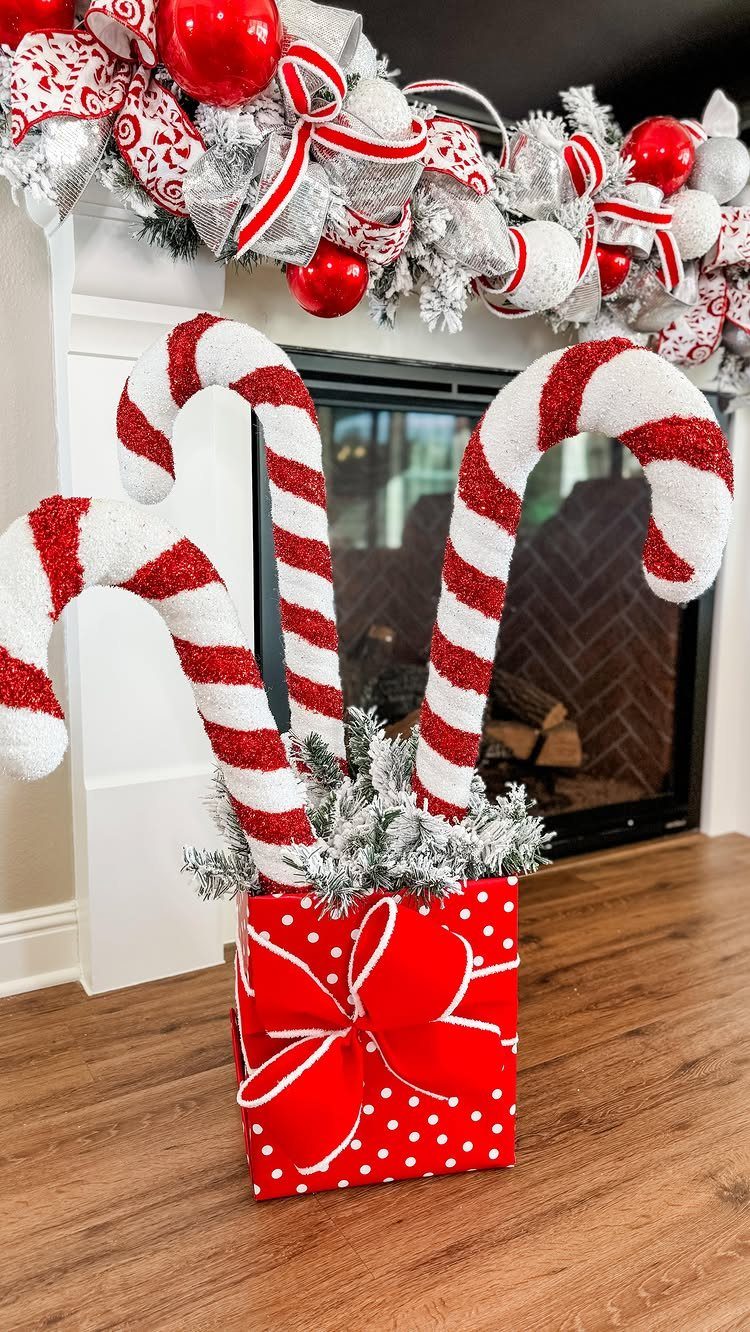 Red polka dot gift box with large candy canes and snowy greenery inside.