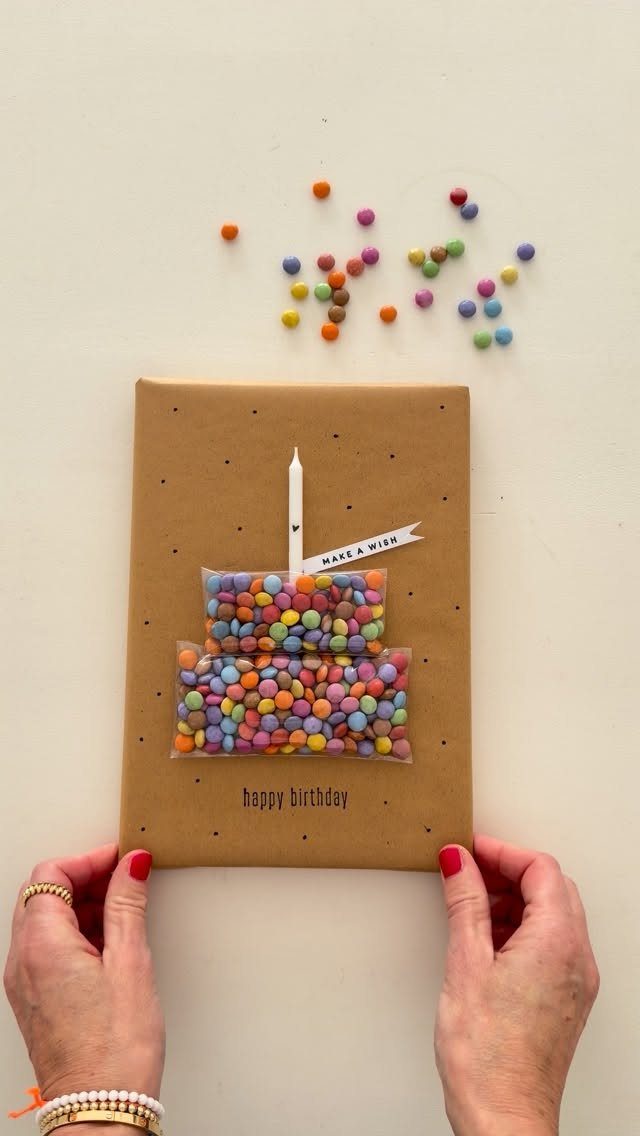 Brown paper wrapped gift with a candy-filled cake pouch and a white candle.