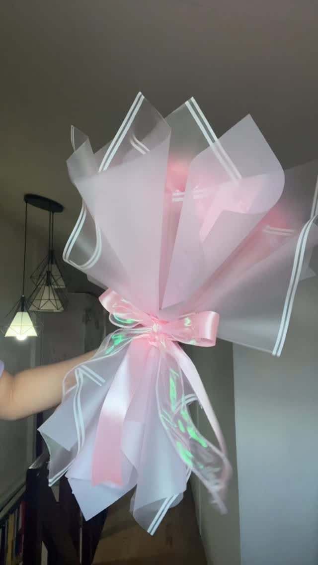 Bouquet-style gift wrap made of translucent pink and white plastic with a pink bow