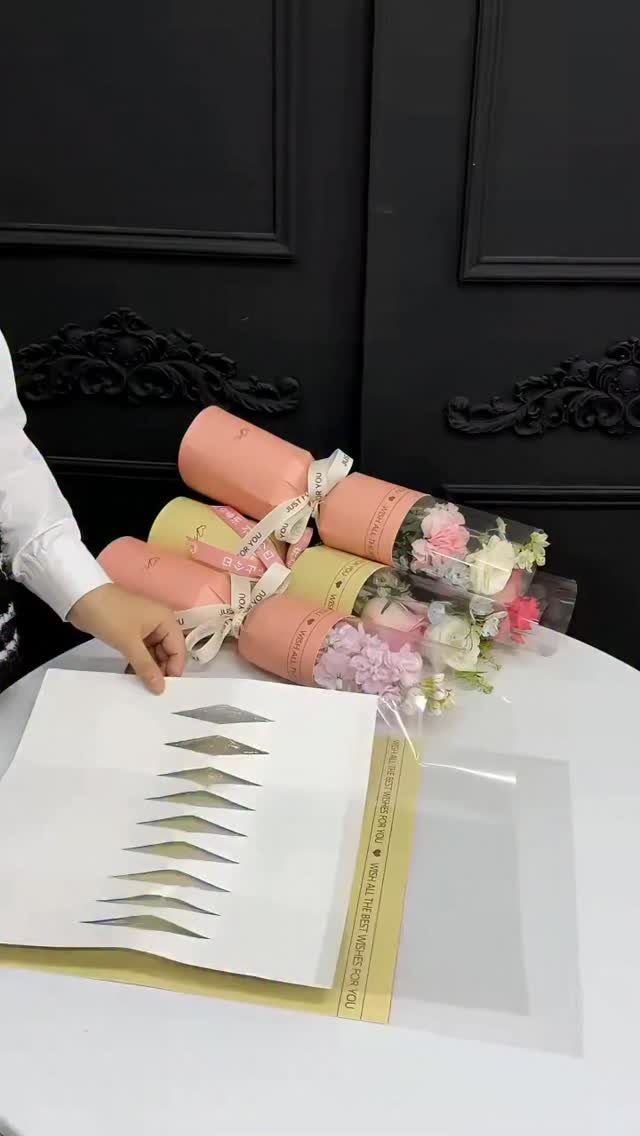 Bouquet of flowers wrapped in pink and yellow rolled paper tubes tied with ribbons