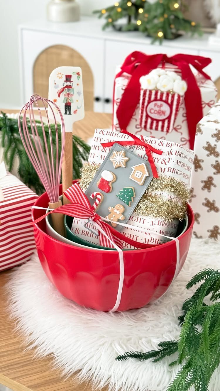 Red mixing bowl filled with kitchen utensils and a wrapped holiday gift.