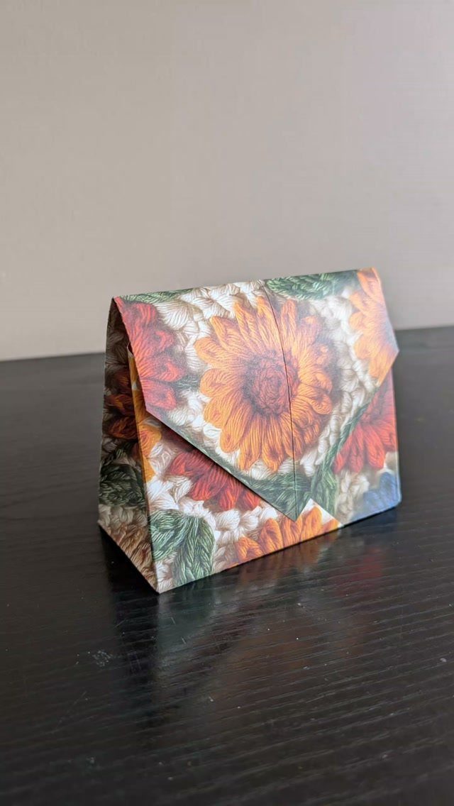 Sunflower patterned wrapping paper gift bag with a folded top flap on dark wood
