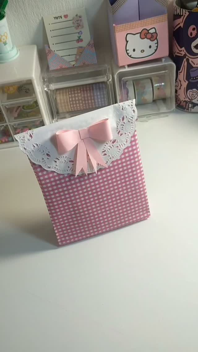 Pink checkered paper gift bag with white lace trim and a pink bow.