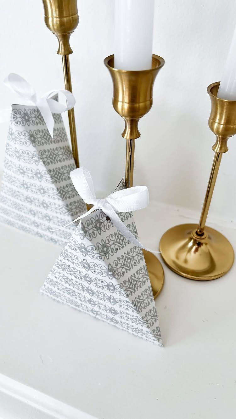 Two triangular grey patterned wrapping paper gift bags with white ribbon bows.