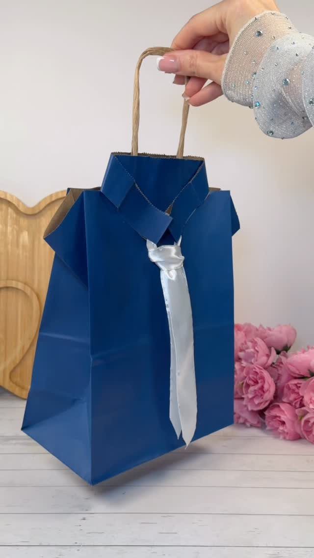 Blue paper gift bag shaped like a dress shirt with a white satin tie.