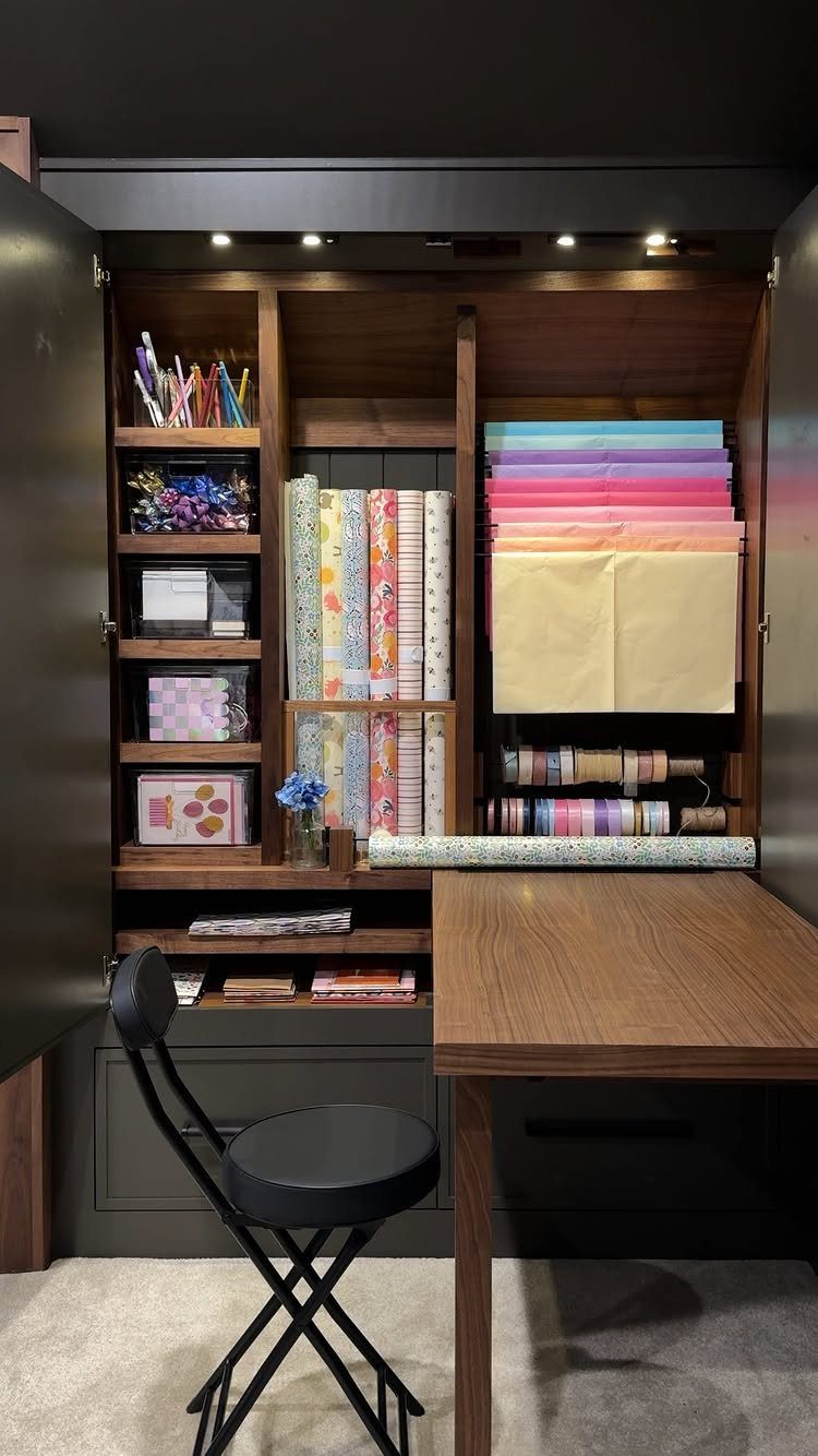 Wooden craft closet with organized rolls of colorful wrapping paper and art supplies.