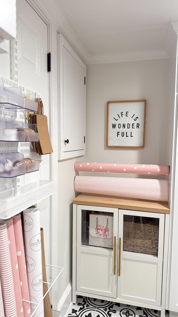 Wrapping paper rolls stored on a white cabinet and in a wire rack.