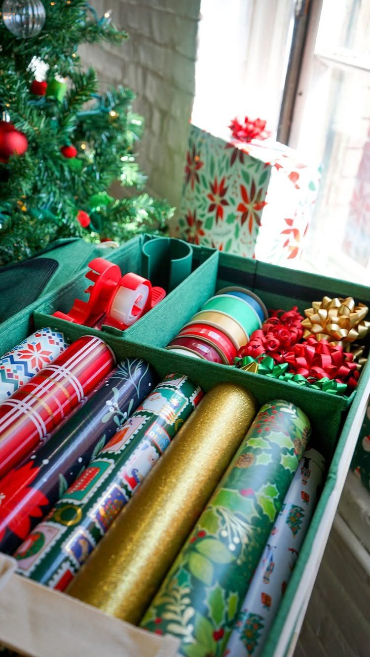 Green organizer bin filled with colorful wrapping paper rolls, ribbons, and festive bows.