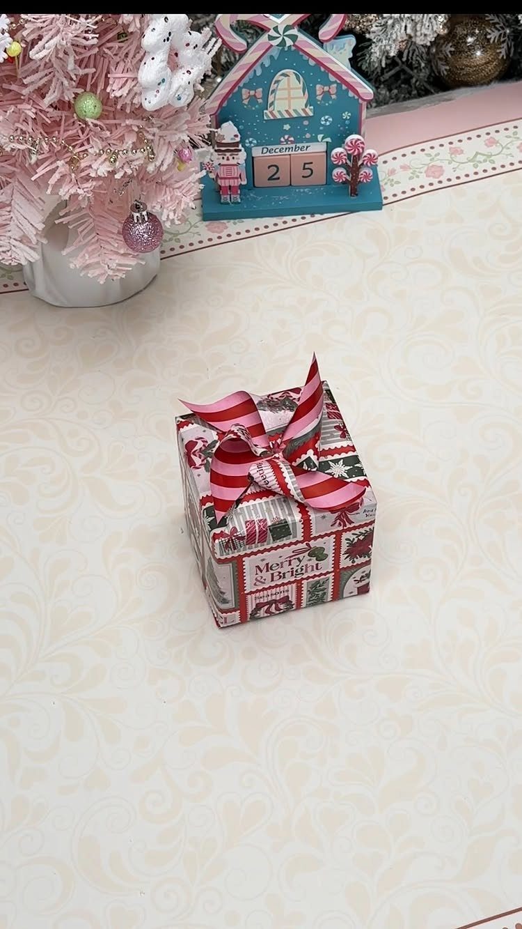 Wrapped Christmas gift with red and white striped bow on a white surface