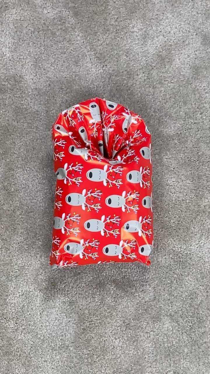 Red gift wrap with white reindeer patterns tied at the top on grey carpet