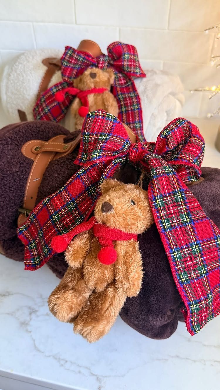 Teddy bear ornaments tied to purple fabric wrapped gifts with plaid bows.